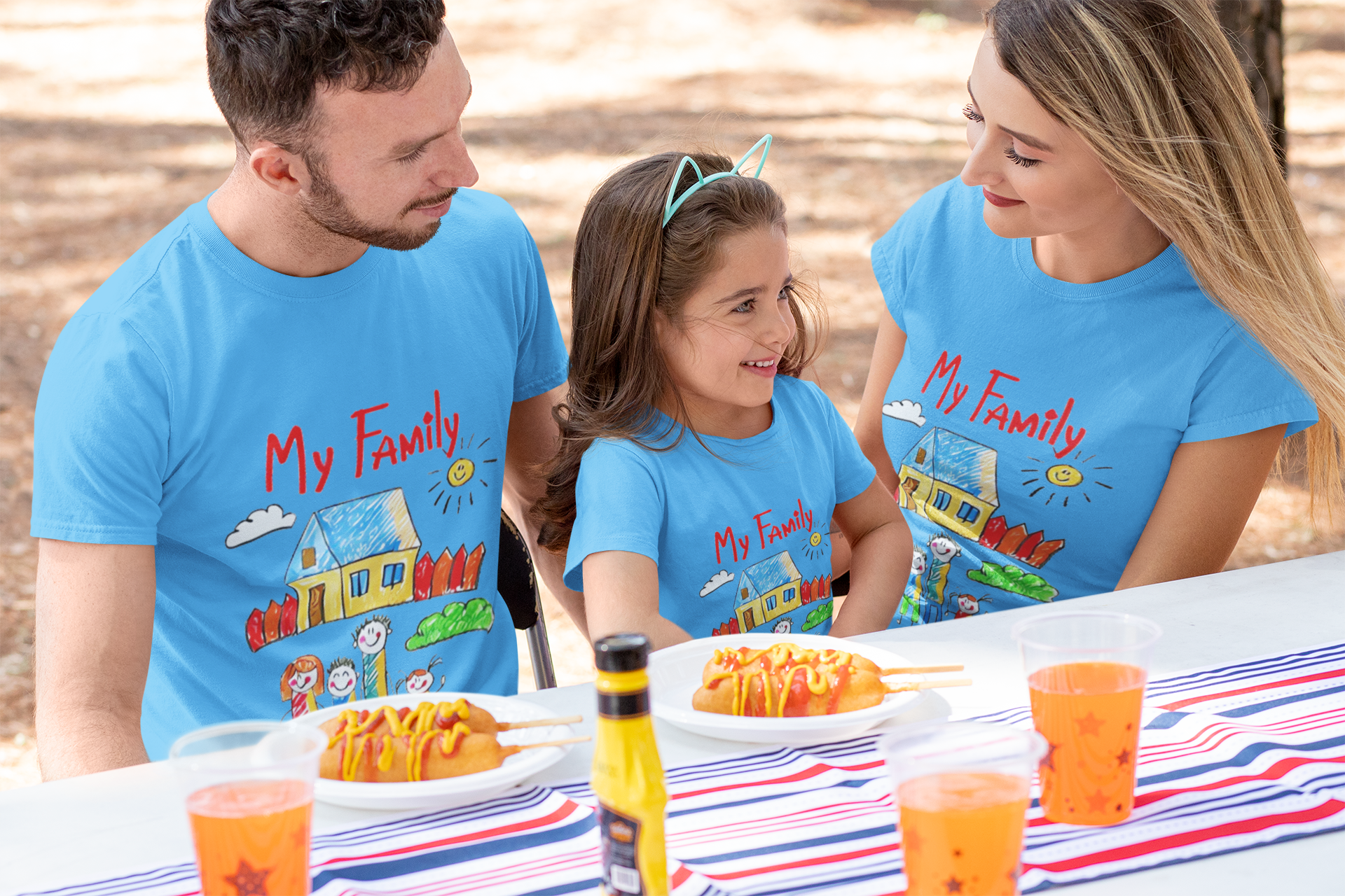 Family wearing matching "My Family" t-shirts, enjoying a meal together outdoors.