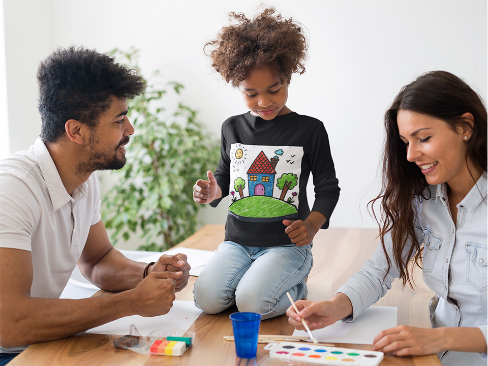 Girl in a house drawing t-shirt, standing between her parents who are painting together.