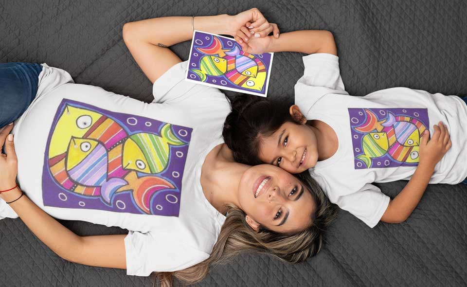 A mother and daughter wearing matching "fish" graphic t-shirts holding their artwork.