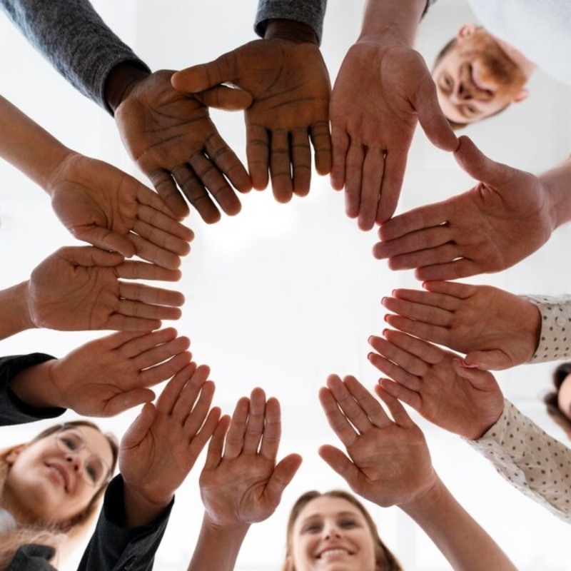 Diverse hands placed in a circle forming unity and collaboration.